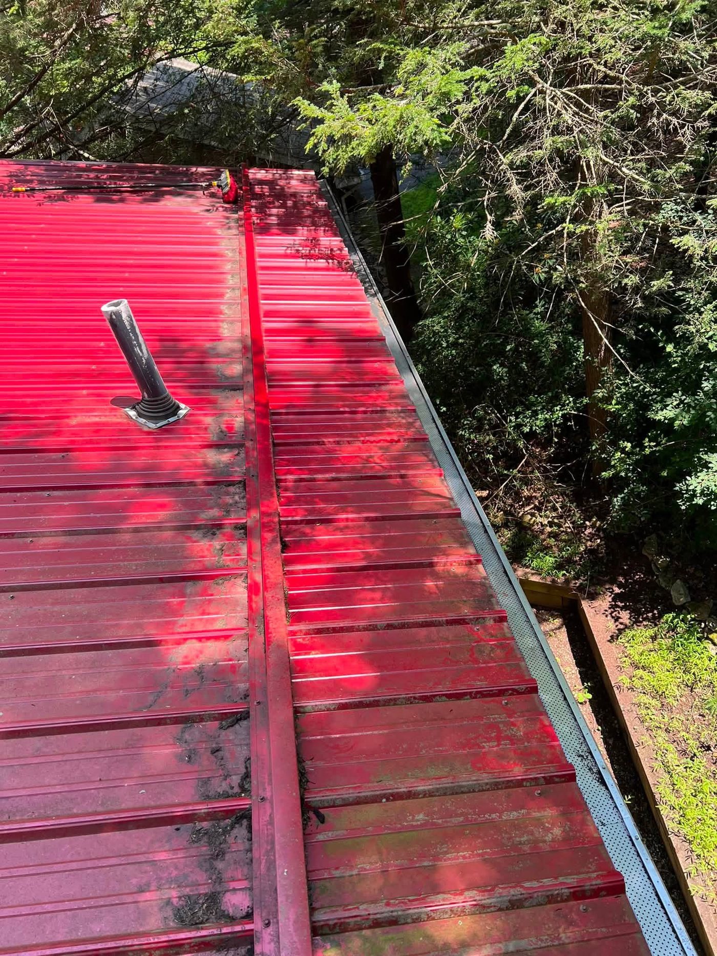Same metal roof and gutter cleared of debris after cleaning
